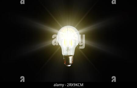 An illuminated or glowing lightbulb on a dark background represents new ideas, innovation, creativity, understanding, knowledge, and inspiration. Stock Photo