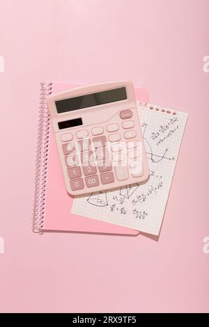 On a pink background, pink school supplies, a calculator, cheat sheets. High quality photo Stock Photo
