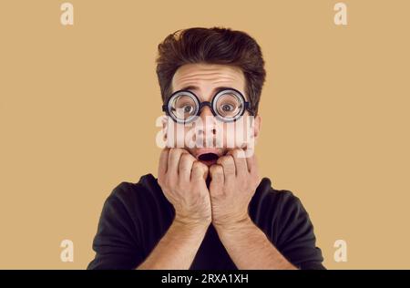 Stunned frightened young man in glasses with thick lenses Stock Photo