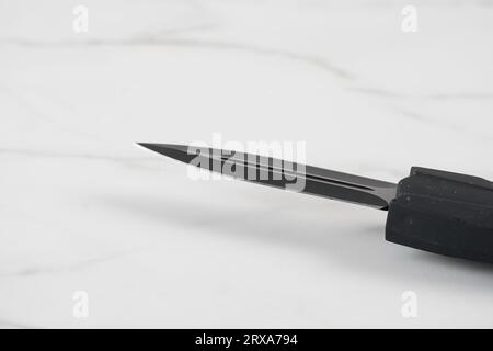 Switchblade (automatic) out-the-front (OTF) knife with black handle and black tactical blade (double edge). Pocket penknife with retractable blade. Stock Photo