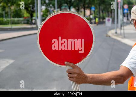 Construction worker holding a Red Stop Sign and directing traffic on the street Stock Photo