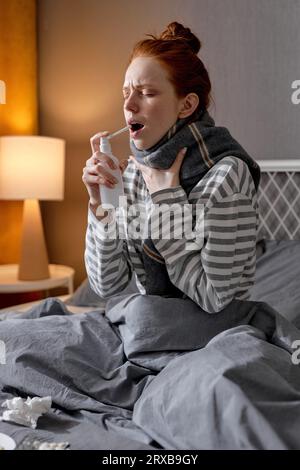 Spray for sore throat. Portrait of unhealthy woman who treats her throat with a spray and sprinkles it in her mouth. The concept of health and disease Stock Photo