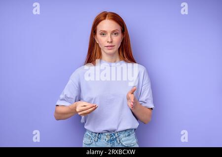 active beautiful ginger deaf woman learning sign language, close up portrait isolated blue background Stock Photo