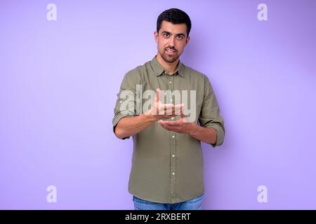 Young deaf mute man using sign language asking how are you, close up portrait isolated blue background Stock Photo