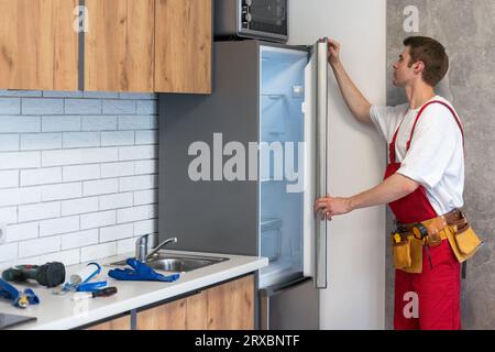Male Worker Repairing Refrigerator With Screwdriver In House Stock Photo