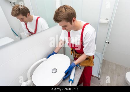 a worker installs a wash basin in a bathroom. Stock Photo