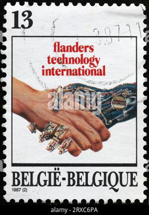 Human hand shaking a robotic hand on postage stamp Stock Photo