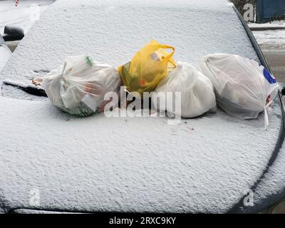 Bags of garbage on the car covered with snow after a blizzard Stock Photo