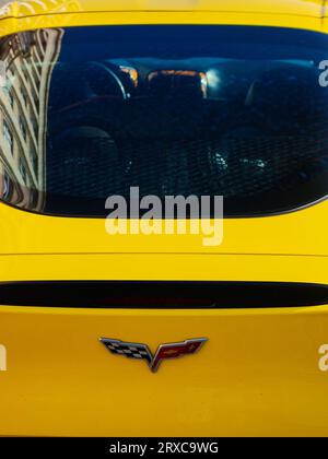 uzhgorod, ukraine - 31 oct 2021: chevrolet corvette logo on a trunk of a yellow sports car. outdoor closeup. old building reflecting in the rear windo Stock Photo