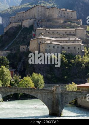 Forte di Bard (Fort of Bard) with alps behind and with bridge over the Dora Baltea river, in the Aosta Valley Region NW Italy, September 24, 2023 Stock Photo