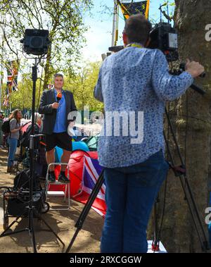 A Tv crew doing a piece to camera at the kings coronation build up on the Mall. With the reporter wearing shorts with his suit attire. Stock Photo