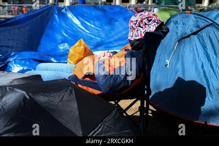 A person asleep sitting in chair with a Union Jack hat over head while camped on the Mall London UK a day before the coronation of King Charles. Stock Photo