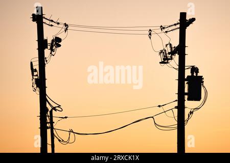 Power pole silhouette of transmission lines at sunset In Alberta Canada. Stock Photo