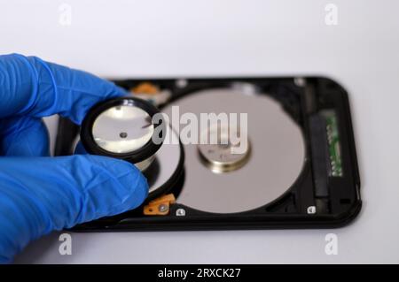 A medical stethoscope on HDD platters and spindle motor, hard disk drive disassembled damaged components, computer maintenance, running diagnostics, r Stock Photo