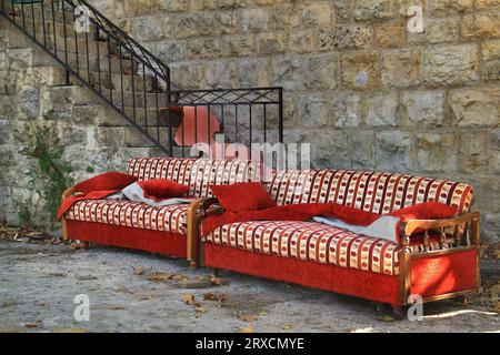 Abandoned old sofas with autumnal design in front of a house in autumn. Stock Photo