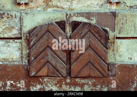 Old vintage small window with closed antique wooden shutters. Stock Photo