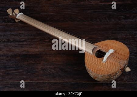 Turkish tambur. Long-necked folk string instrument of the lute family on wooden table. Stock Photo