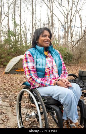 A disabled woman enjoys nature at a campsite. Being in a wheelchair doesn't stop her from enjoying the outdoors. Stock Photo