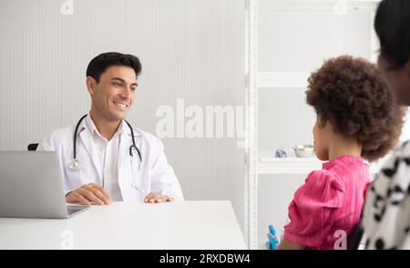 Hispanic physician meeting and diagnosis mixed-race afro children with her African American mother at a hospital. The doctor using stethoscope and do Stock Photo