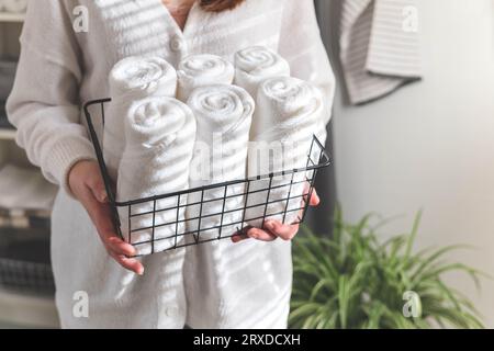 Woman's hands neatly putting or displaying a clean rolled up white towels made from organic cotton. Stock Photo