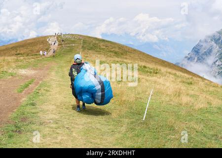 Paraglider pilot with his paraglider on his way to the top of Monte Baldo on Lake Garda near Malcesine Stock Photo