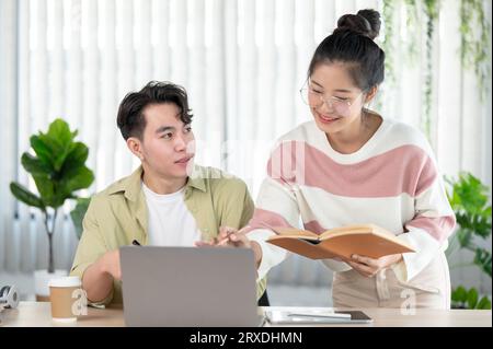 A friendly and kind Asian female friend is helping her friend with math lessons, tutoring, and preparing for the exam with her friend at home. Educati Stock Photo