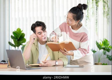 A friendly and kind Asian female friend is helping her friend with math lessons, tutoring, and preparing for the exam with her friend at home. Educati Stock Photo