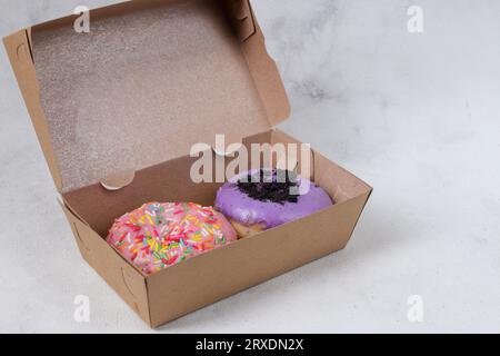 Delicious sweet donuts with different flavors in small paper box. Isolated image on white background Stock Photo