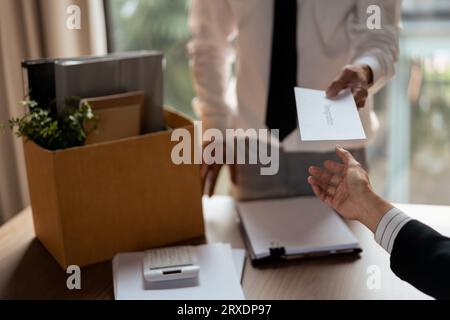 Male employee with belongings cardboard box sending resignation letter to executive for leaving job. Stock Photo