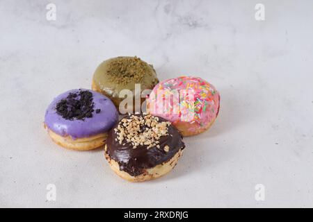 Delicious sweet donuts with different flavors on a table. Isolated image on white background Stock Photo