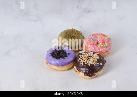 Delicious sweet donuts with different flavors on a table. Isolated image on white background Stock Photo