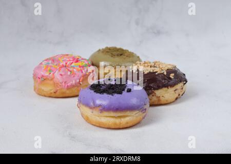 Delicious sweet donuts with different flavors on a table. Isolated image on white background Stock Photo