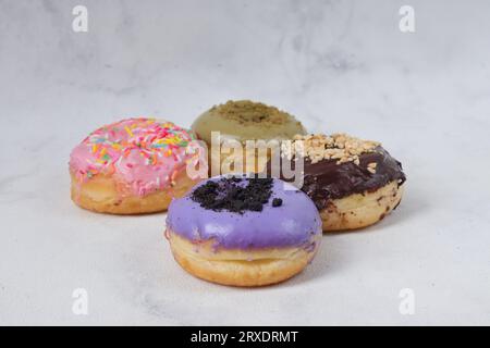 Delicious sweet donuts with different flavors on a table. Isolated image on white background Stock Photo