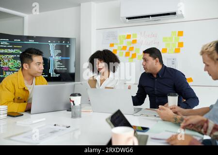Group of developers discussing project in weekly meeting with team leader Stock Photo