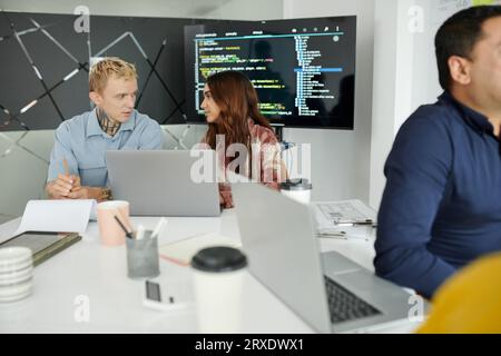 Software developers discussing and fixing bugs in programming code Stock Photo