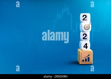 2024 new year goal and success, business resolutions and financial concepts. New year number with target icon on dices stack on growth graph on wooden Stock Photo