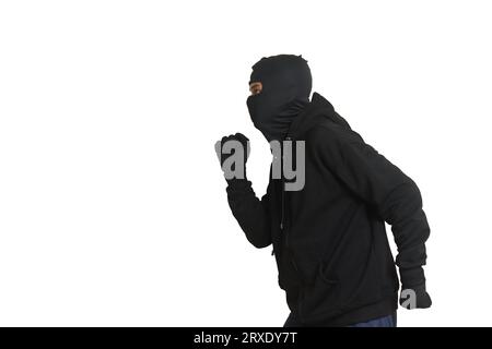 Side view portrait of a masked thief wearing black hoodie sneaking forward and walking slowly. Isolated image on white background Stock Photo