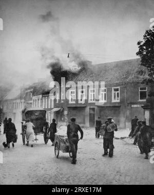 Fleeing refugees passing through a burning village in the Low Countries on the 10-11th May 1940, during the Second World War. Stock Photo