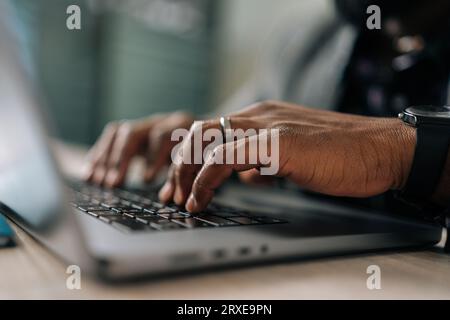 Close-up hands of unrecognizable black businessman working on laptop at home office. Young African student or remote teacher using computer remote Stock Photo