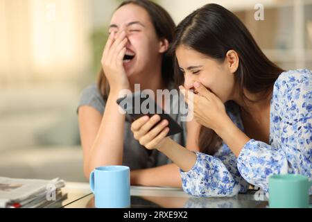 Funny friends watching media on phone laughing loud at home Stock Photo