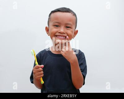 little asian boy holding a toothbrush while smiling on white background with copy space. children's dental health concept Stock Photo