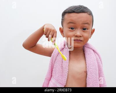 little asian boy holding a toothbrush on white background with copy space. children's dental health concept Stock Photo