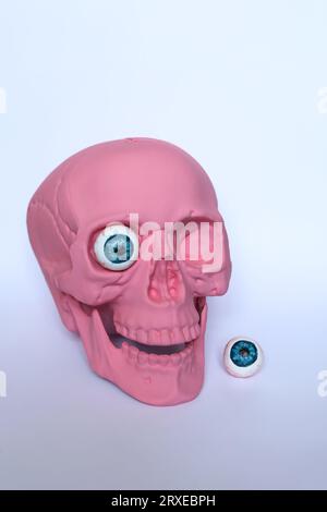 a pastel pink skull with eyeballs on a white background halloween concept Stock Photo