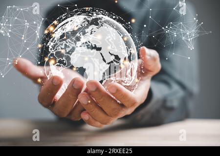 A businessman's hand holds a globe, illustrating seamless connectivity and data flow across global network Stock Photo
