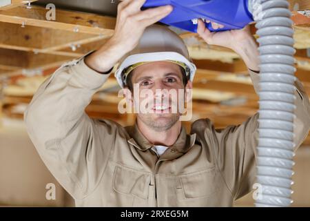 male builder installing ventilation unit Stock Photo