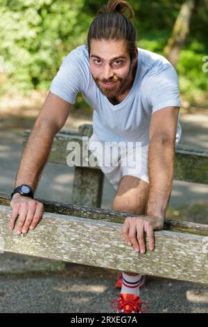 young fit man stretching legs outdoors doing forward lunge Stock Photo