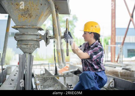 female builder using cement mixer on building site Stock Photo