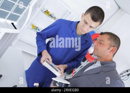 technicians operating remote control for air conditioning unit Stock Photo