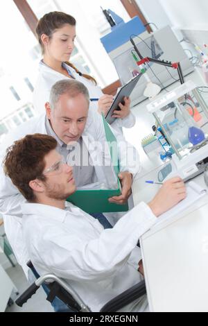 male medical researcher in wheelchair performs tests with blue liquid Stock Photo