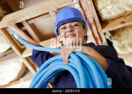 female worker fitting ventilation system in construction site Stock Photo